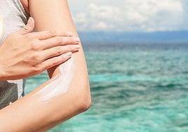 Una mujer se aplica protector solar en el brazo.