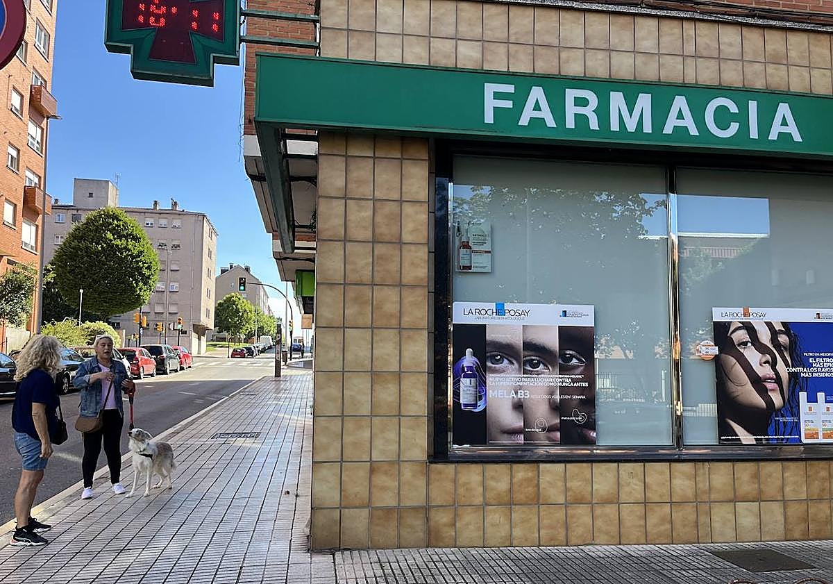 Imagen principal - Farmacia en la que trabajaba el fallecido y flores depositadas en la puerta del negocio.