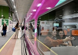 Varios viajeros se suben al tren AVLO de Renfe, unidad que estrenará en la línea Gijón-Madrid con su característico color morado.