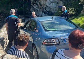 Agentes de la Policía Local de Llanes, junto al coche atrapado.