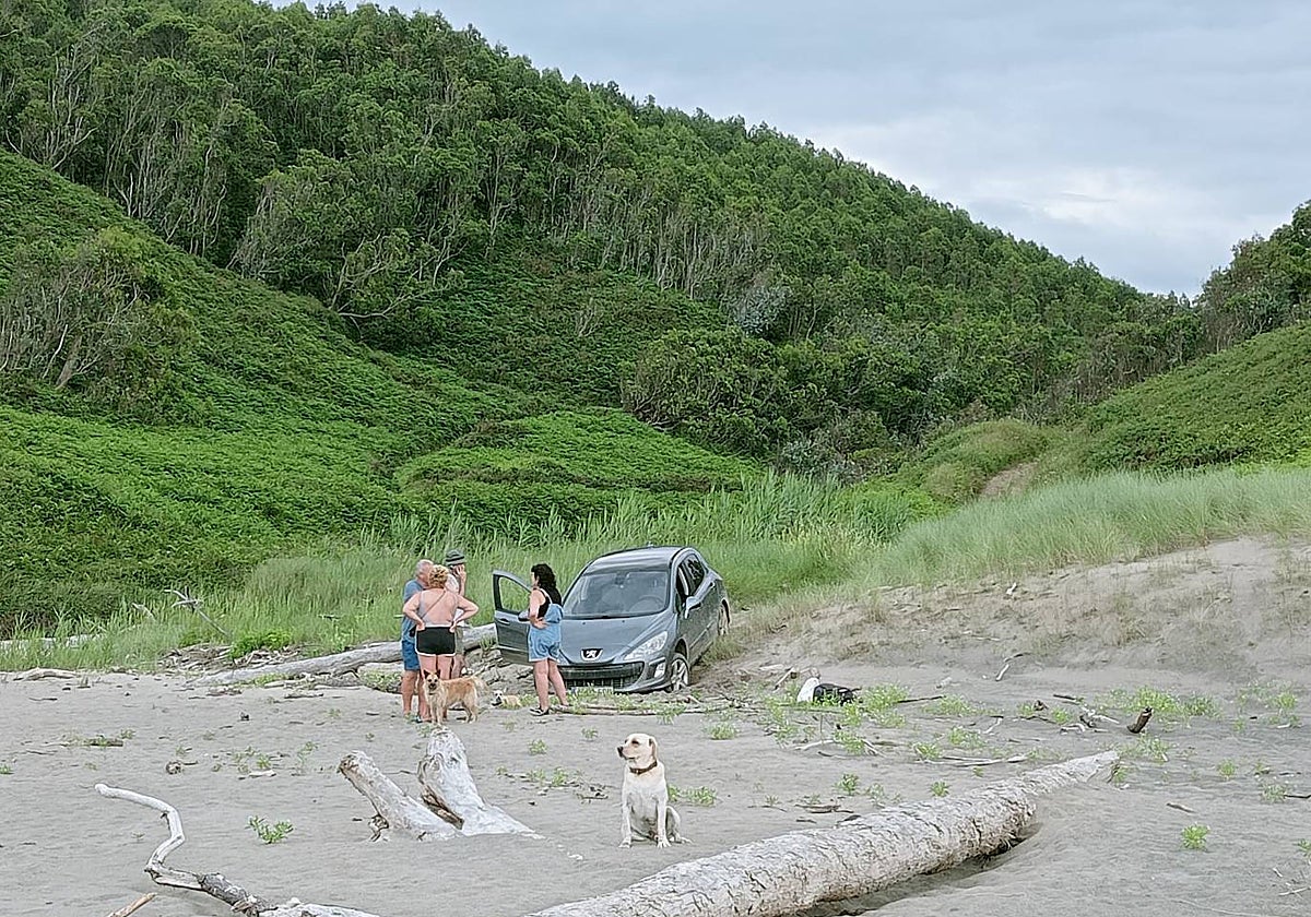 Los turistas, pidiendo ayuda para sacar su coche de la arena en el Playón de Bayas.