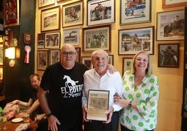 Agustín, José Manuel y Luci Buznego, con la página enmarcada de EL COMERCIO de hace 50 años, cuando abrió el bar.