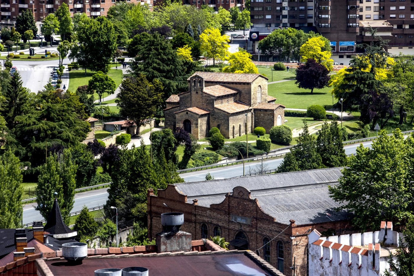 A la izquierda, la iglesia de San Julián de los Prados junto al Bulevar de Santullano que se pretende sustituir con el nuevo vial por dentro de la fábrica de armas.