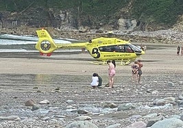 Varias personas se lamentan por lo ocurrido, ante el helicóptero de rescate de Bomberos, en la Concha de Artedo.