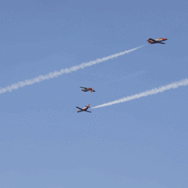 Personas en el arenal de San Lorenzo, sin bañarse, al comienzo de los primeros ensayos de las aeronaves para el Festival Aéreo de Gijón.