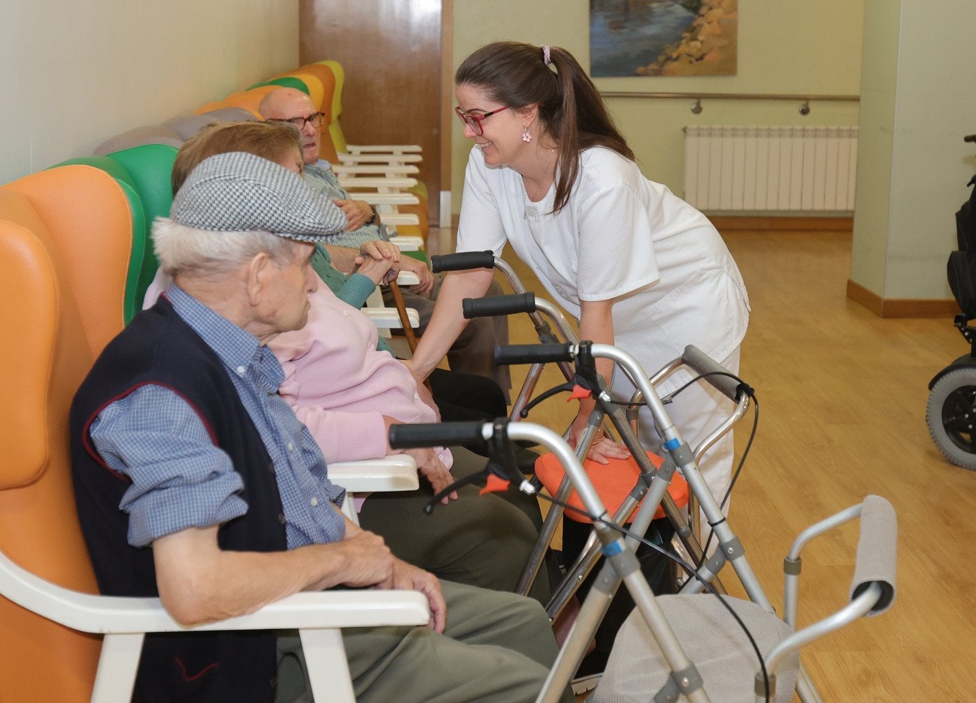 Una auxiliar de geriatría conversa con algunos usuarios de una residencia para mayores.