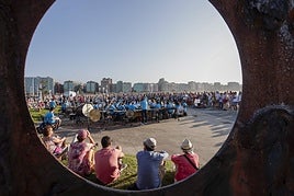 La Banda Sinfónica de Gijón interpretó piezas de cine junto a 'Sombras de luz', icónica escultura de Fernando Alba, en el Muro.