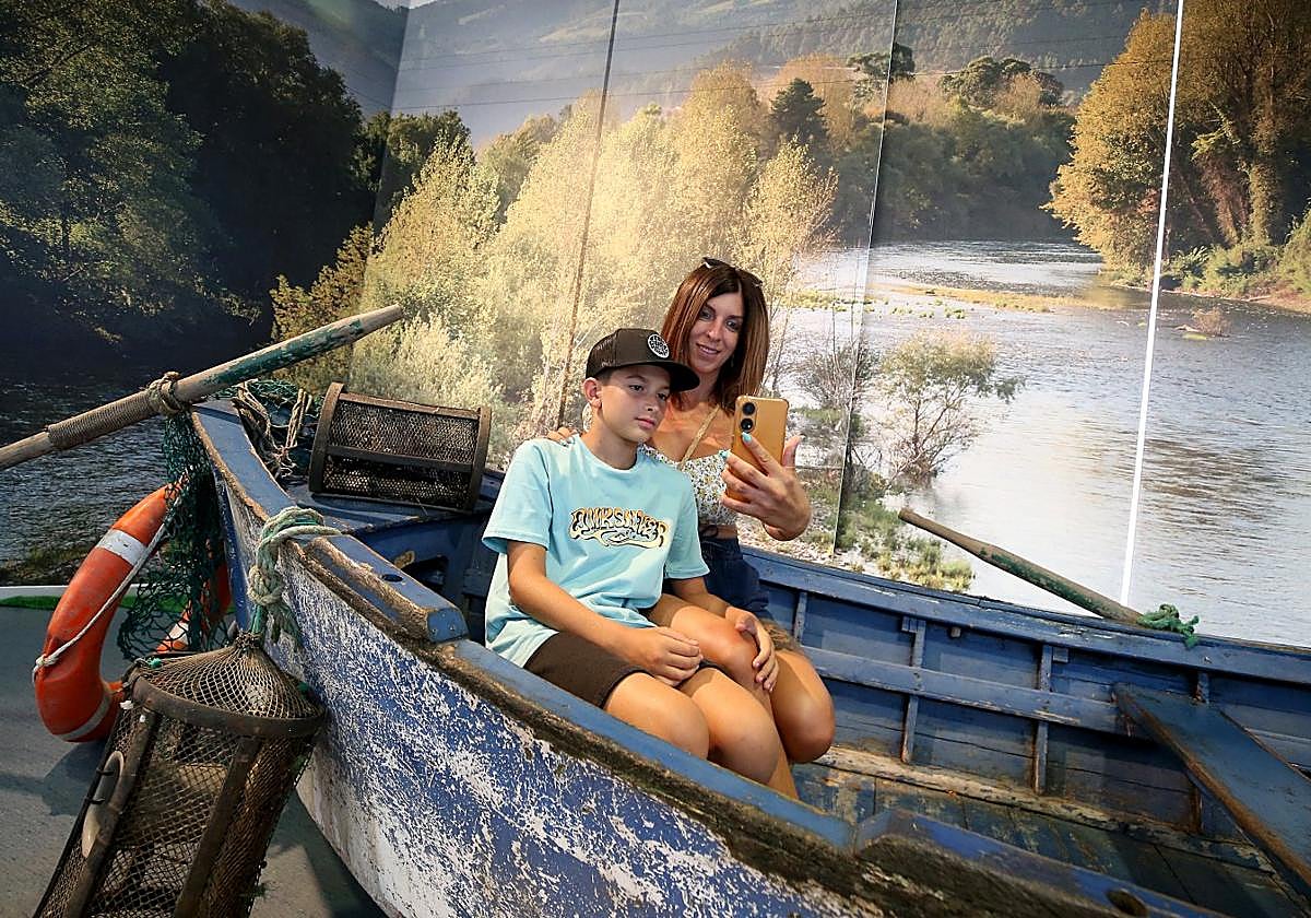 Paula Sánchez, sonriente mientras posa y sostiene su teléfono para inmortalizar con su hijo pequeño, Neizan Villanueva, su paso por una barca en el pabellón del Principado, que este año está dedicado al agua.