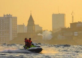 Un pareja experimenta la velocidad de una moto acuática en la costa de Gijón.