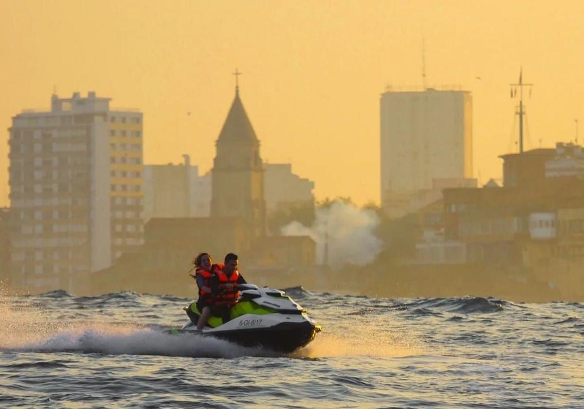 Un pareja experimenta la velocidad de una moto acuática en la costa de Gijón.