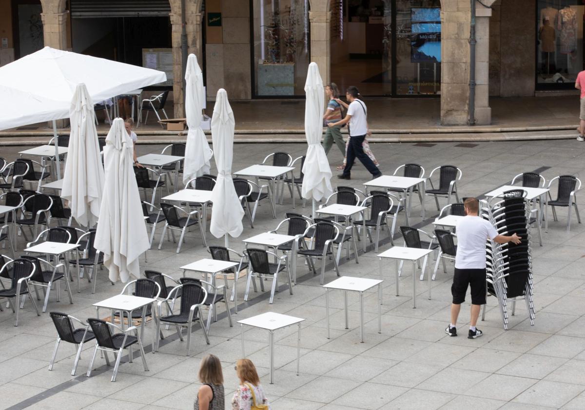 Un camarero coloca una terraza en la plaza de España, en Avilés.