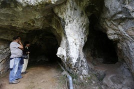 Dos personas visitando la cueva de la LLuera, que contiene grabados de animales.