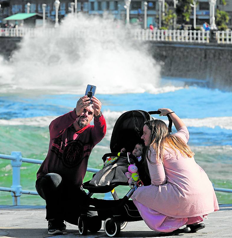 Una pareja y su bebé se fotografían en la escalera 2 de la playa de San Lorenzo.