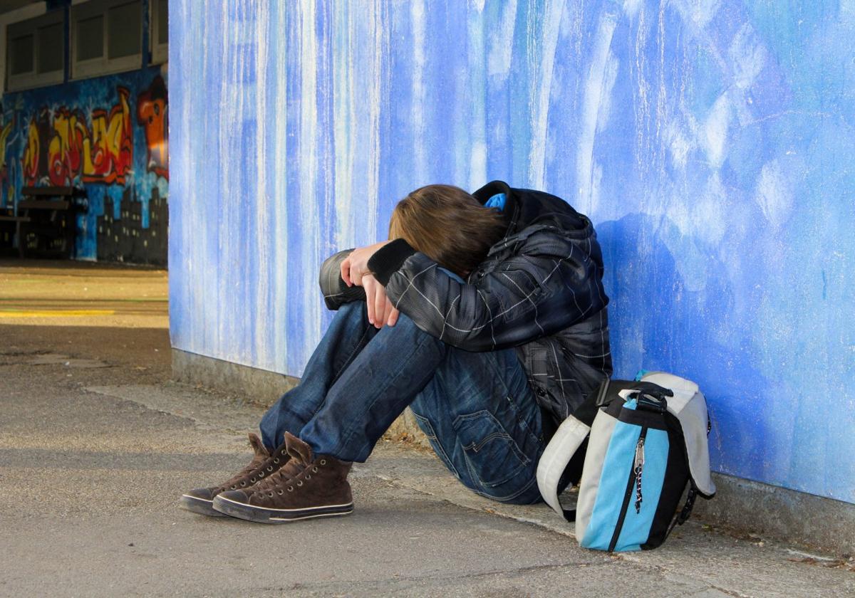 Un adolescente en posición de autoprotección tras sufrir acoso en un centro educativo.