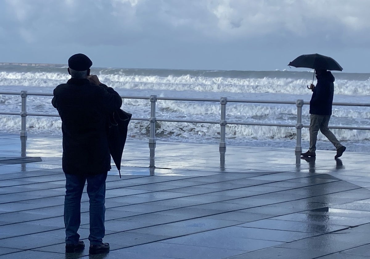 Dos personas disfrutan del paseo del Muro en un día lluvioso