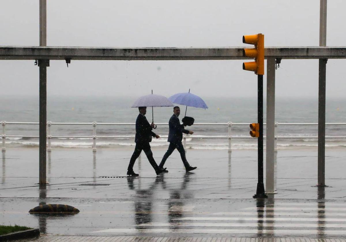 Dos personas pasean por el Muro de Gijón durante las constantes lluvias caídas el pasado miércoles.