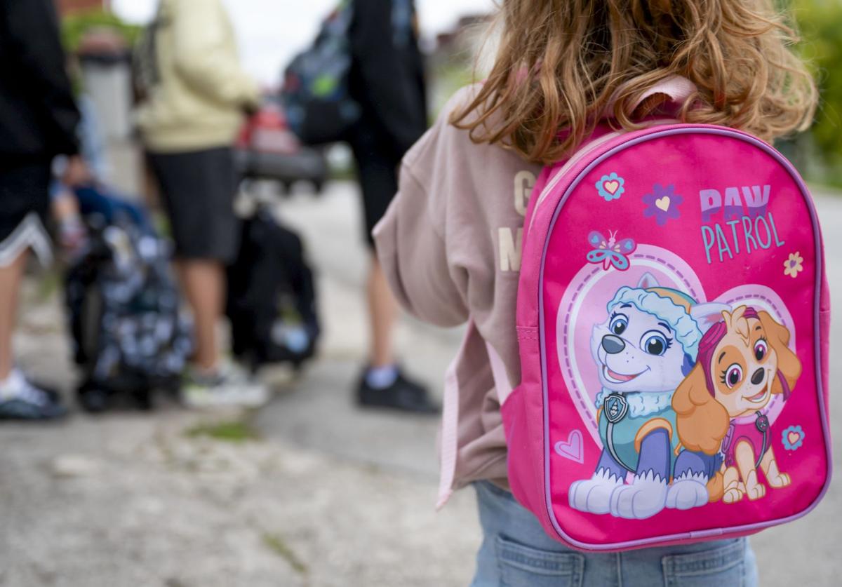 Una niña espera el transporte escolar.