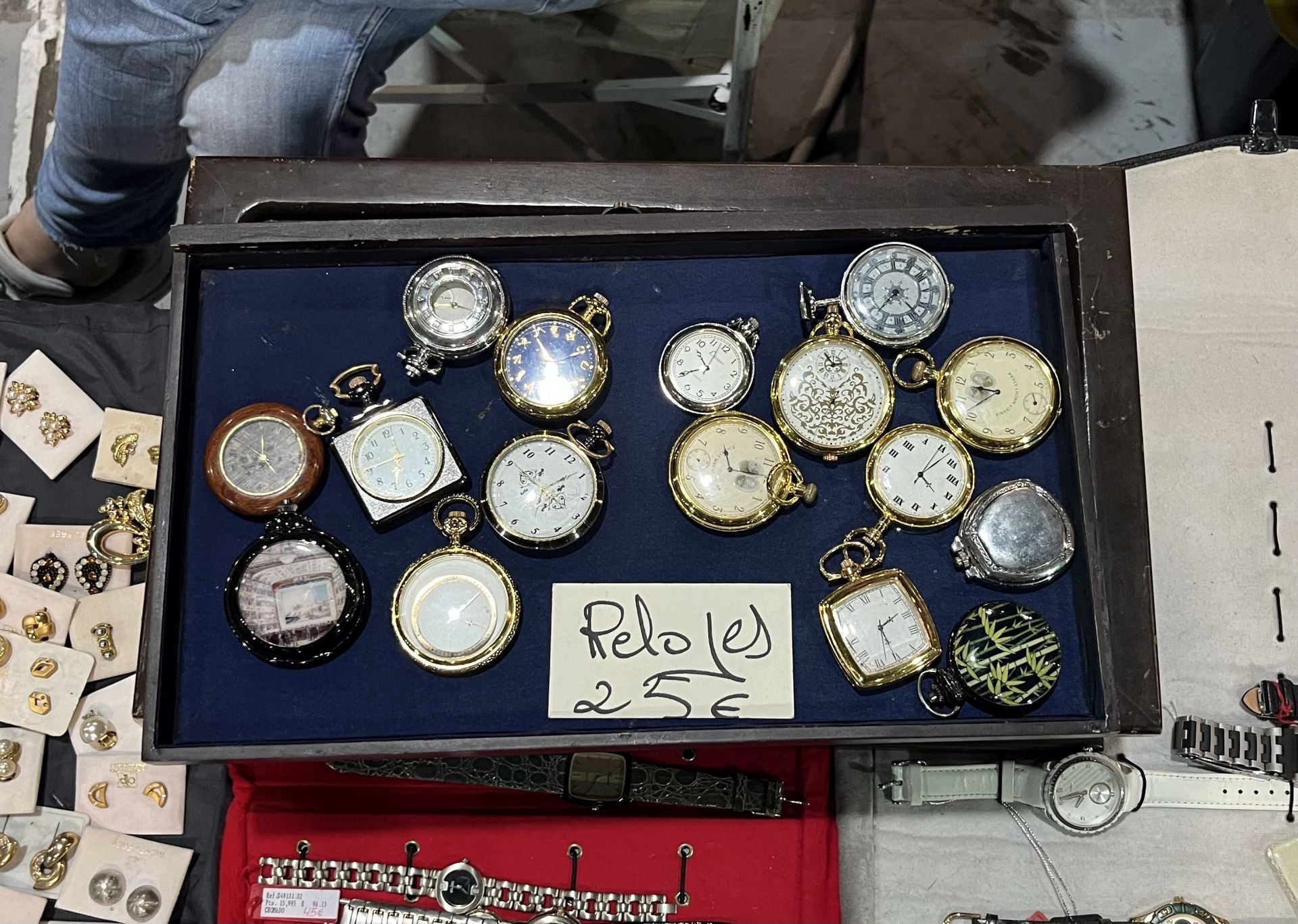 Son reproducciones de pila de relojes de bolsillo del siglo XX. Están en el puesto de Lilaines (expositor 76) y tienen un precio de 25 euros cada uno. Si fuesen de cuerda, habría que añadir un cero más a la cifra.