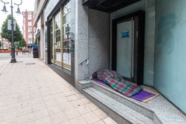 Una persona duerme en la entrada de un banco en Avilés.