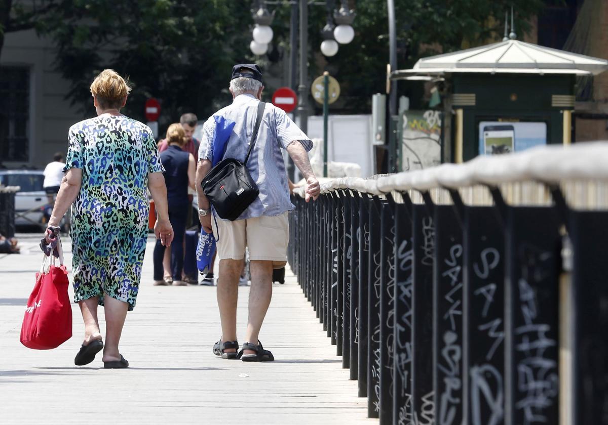 Una pareja de personas de avanzada edad pasea por la calle.