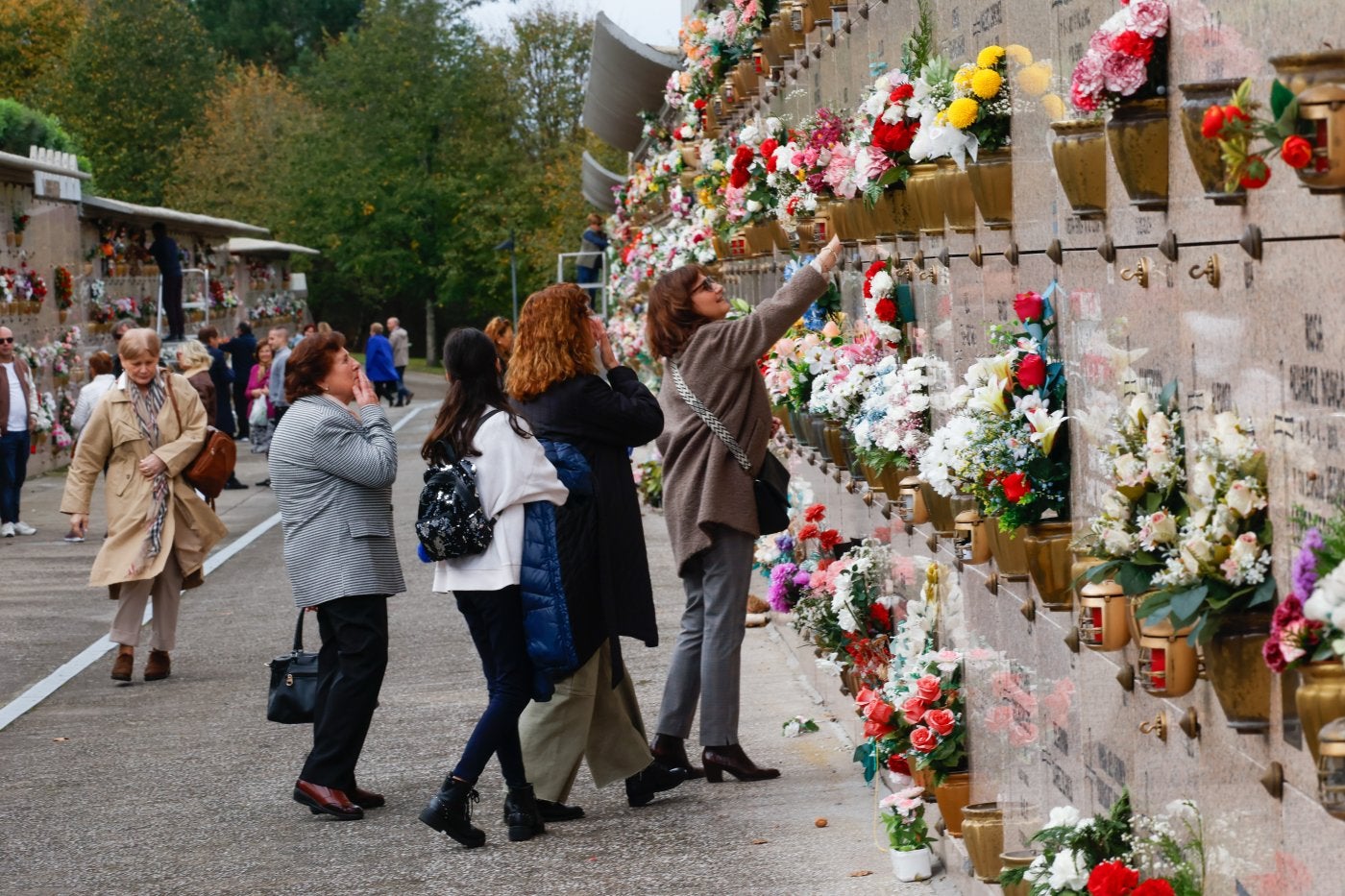 Una familia coloca flores en un nicho del cementerio de Deva.