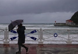 Una joven sortea el viento paseando junto a la playa de Santa Marina, en Ribadesella.