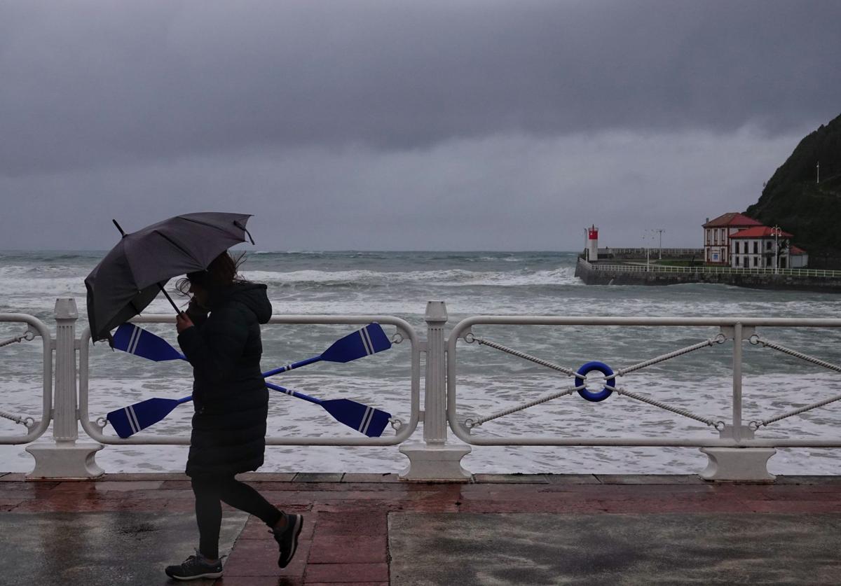 Una joven sortea el viento paseando junto a la playa de Santa Marina, en Ribadesella.