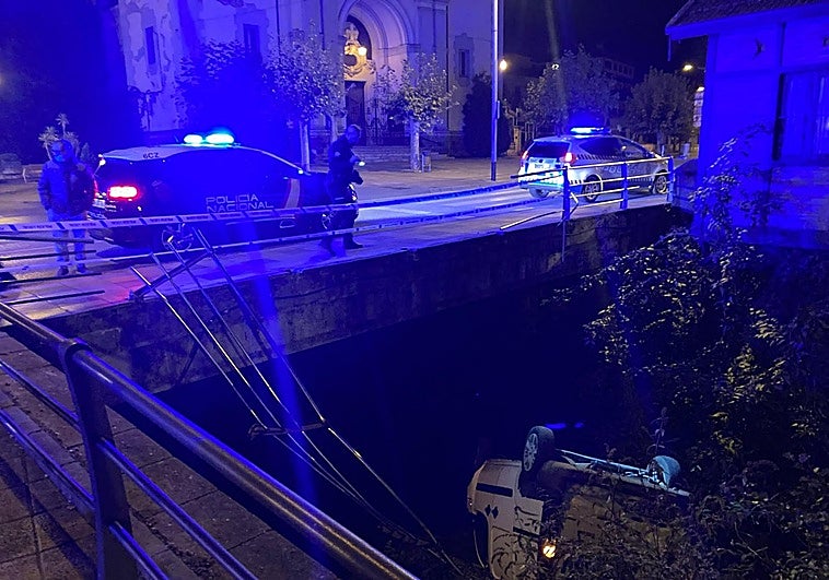 El vehículo, volcado en el fondo del río San Juan en Mieres, se llevó por delante las barandillas.