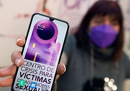 Una mujer sostiene el teléfono con el fondo de pantallas del Centro de Crisis para Víctimas de Agresiones Sexuales.