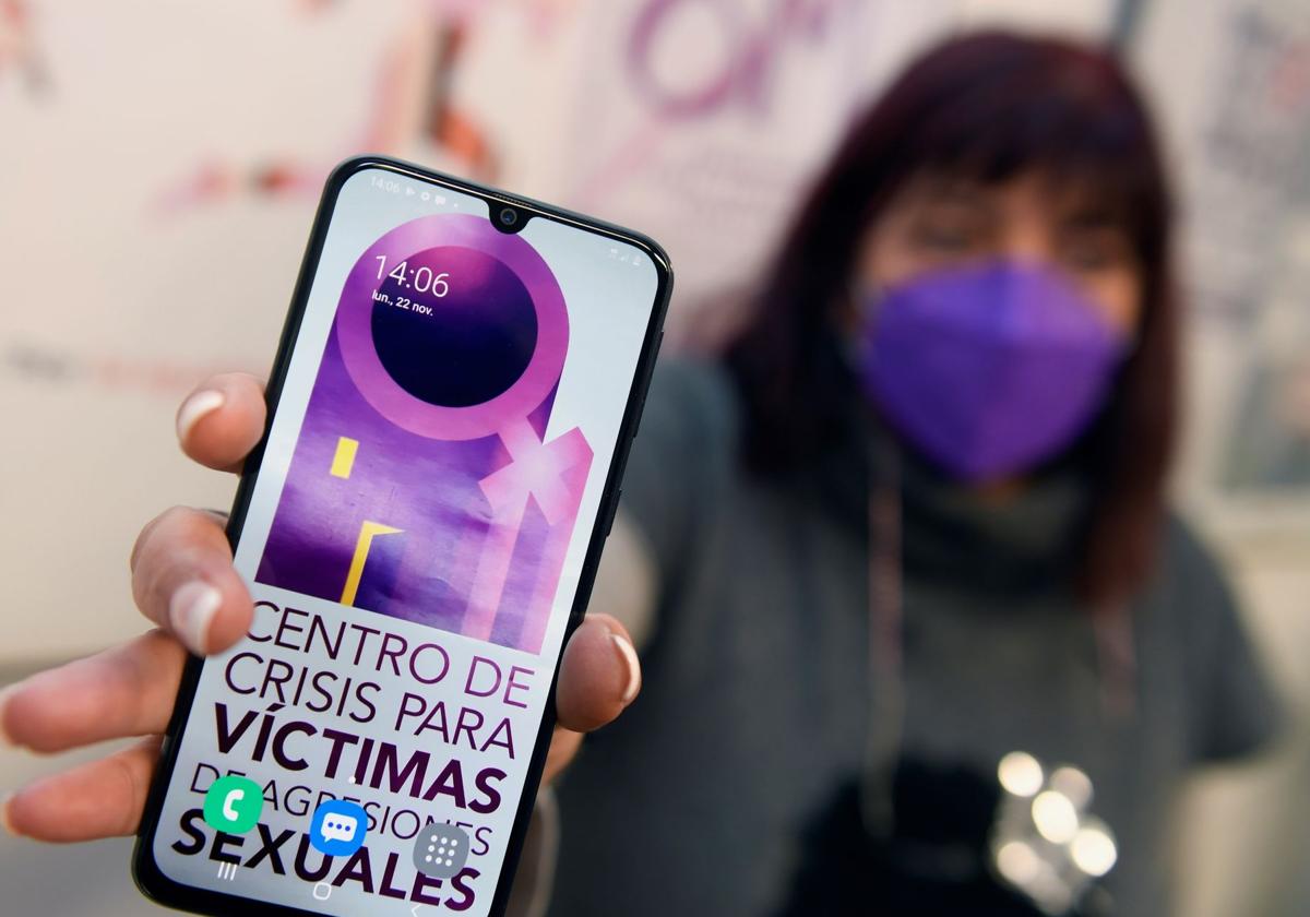 Una mujer sostiene el teléfono con el fondo de pantallas del Centro de Crisis para Víctimas de Agresiones Sexuales.