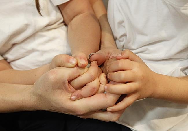 María, con las manos de sus hijas.