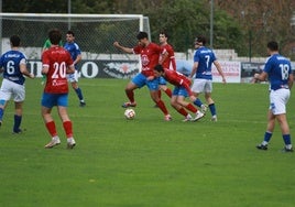 Dos jugadores del Ceares se llevan el balón en presencia de Iván Elena.