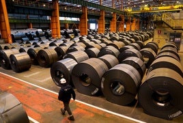 Un trabajador pasa por delante de unas bobinas de acero.