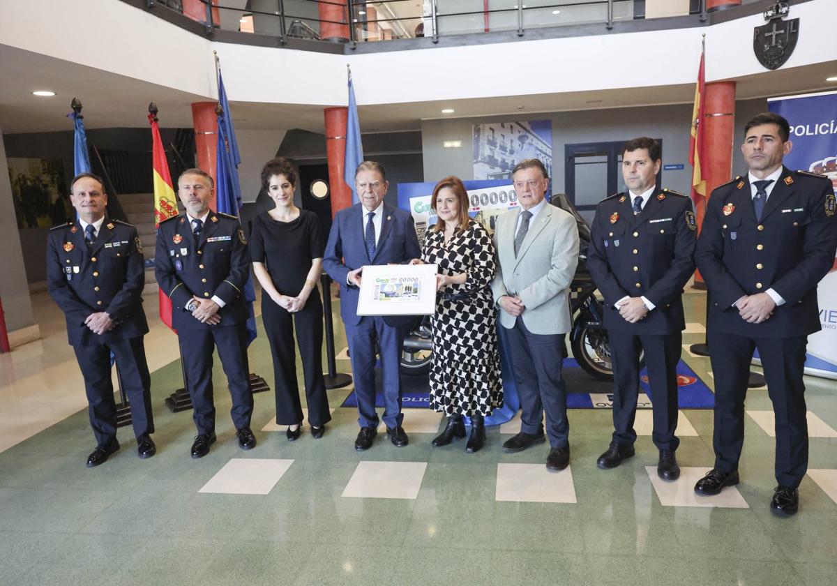 Alfredo Canteli y Yobanka Cuervo, en el centro, sujetan la reproducción del cupón de la ONCE que homenajea a la Policía Local de Oviedo en el cuartel de Rubín.