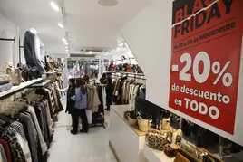 Clientes observan prendas con descuentos por el 'black friday' en un comrcio de moda de la calle de La Cámara.