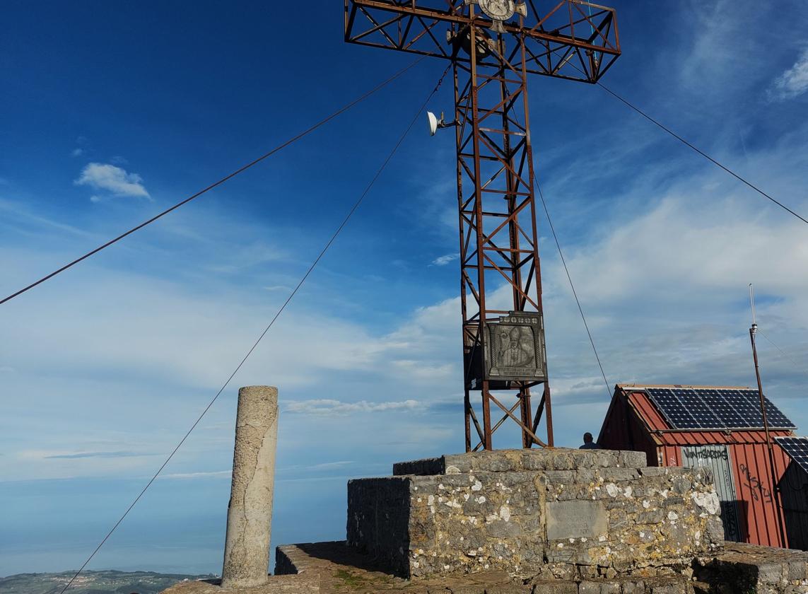 Cruz de Pienzu, a 1161 metros, y -al fondo- la zona de costa de la que parte esta excursión, una circular de 20 kilómetros que enlaza mar, bosque y montaña deambulando -de abajo a arriba- la espectacular sierra del Sueve