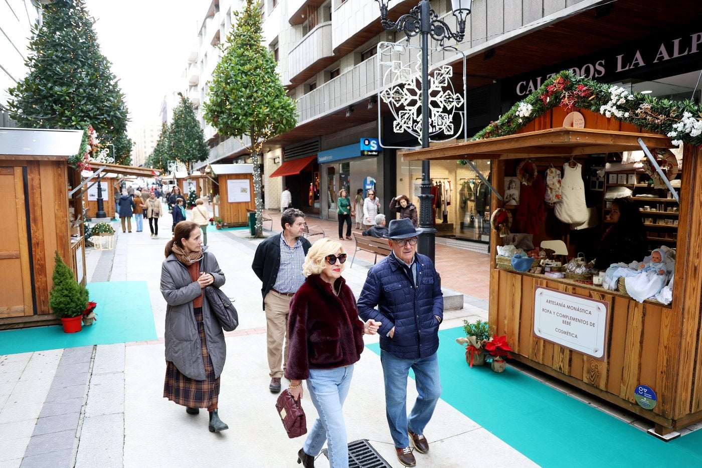 Grupos de personas pasean por la calle de Gil de Jaz y miran las casetas con los productos de los monasterios.