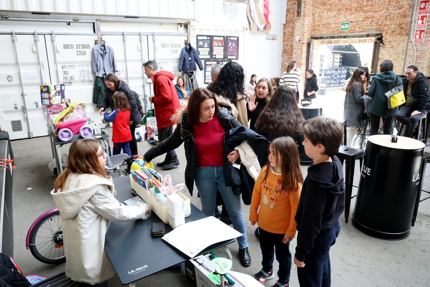 Una madre y dos niños en el puesto de una de las pequeñas participantes del mercadillo navideño del Kuivi de Almacenes Industriales.