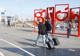 Dos turistas pasan delante de las 'Letronas' con sus maletas de mano.