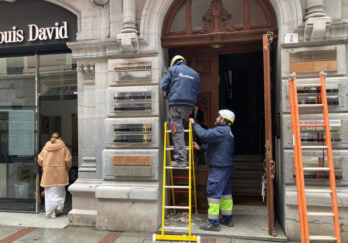 Los operarios, arreglando la avería en el cuadro del portal del número 2 de la calle Langreo.