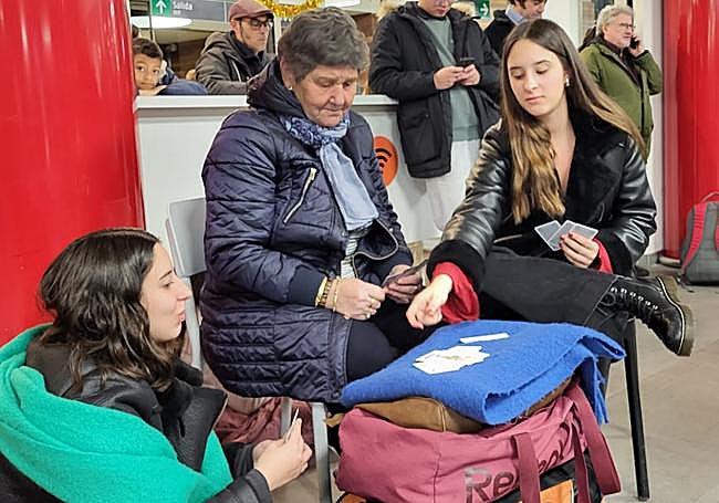 Algunos viajeros aguantando la espera con más filosofía y entre cartas.