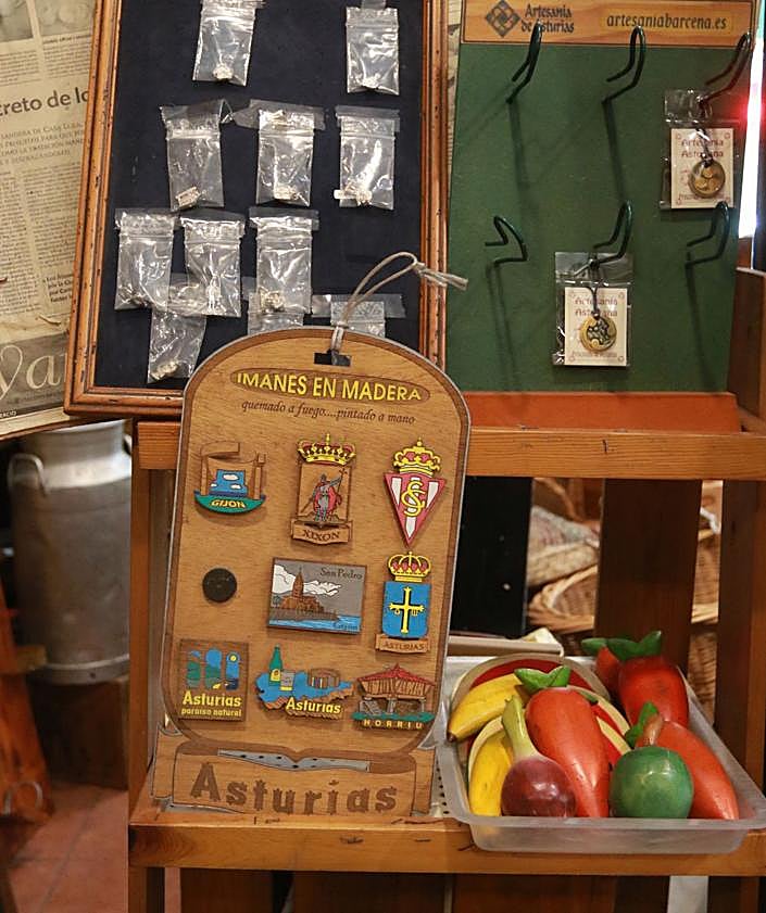 Imagen secundaria 2 - Arriba, estanterías repletas aún de objetos; a la izquierda, paellera con imanes, cestería y escanciadores y a la derecha, imanes asturianos y al fondo una lechera tradicional. 