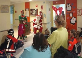 Los niños saludan a Papá Noel, el elfo mago y los bomberos a su llegada a la planta de Pediatría.