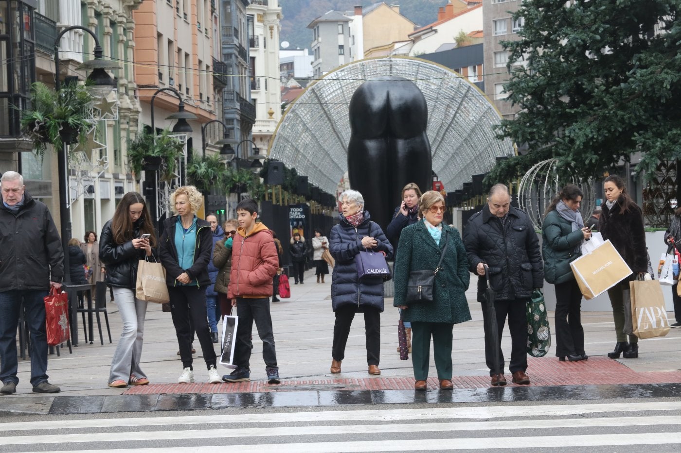 Varias personas llevando bolsas a la altura de la calle en Palacio Valdés de Oviedo.