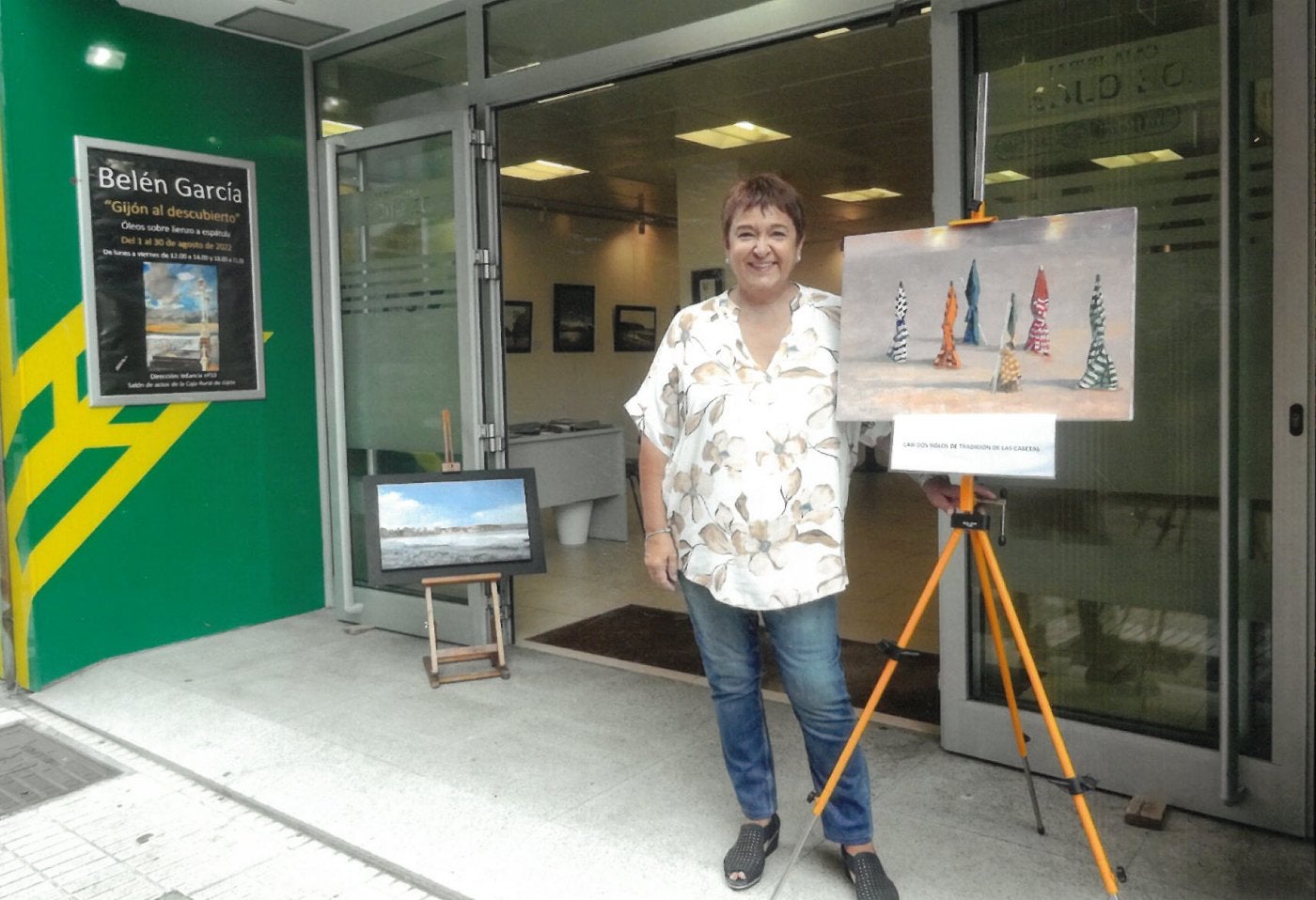 La pintora gijonesa en la entrada de una de sus exposiciones en la Caja Rural de Gijón.