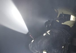 Un bombero sofoca las llamas en el interior de la vivienda.