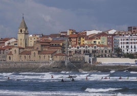 Surfistas en la playa de San Lorenzo con la iglesia de San Pedro al fondo.