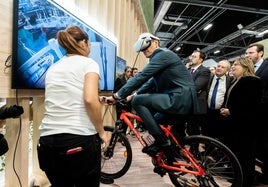 Pedro Sánchez prueba la bici con realidad virtual instalada en el estand de Asturias en Fitur.