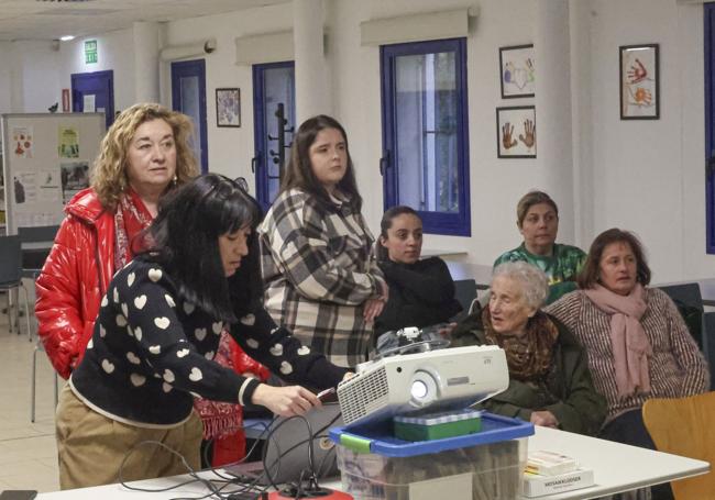 Mayda Bedia, miembro del equipo de Medio Ambiente de ArcelorMittal Asturias, prepara la presentación, con varias vecinas de Llaranes detrás.