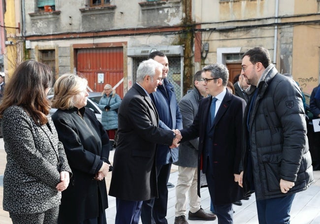 El Ministro de Justicia saluda al presidente del TSJA ante el nuevo palacio, con una de las casas en muy mal estado de la zona.